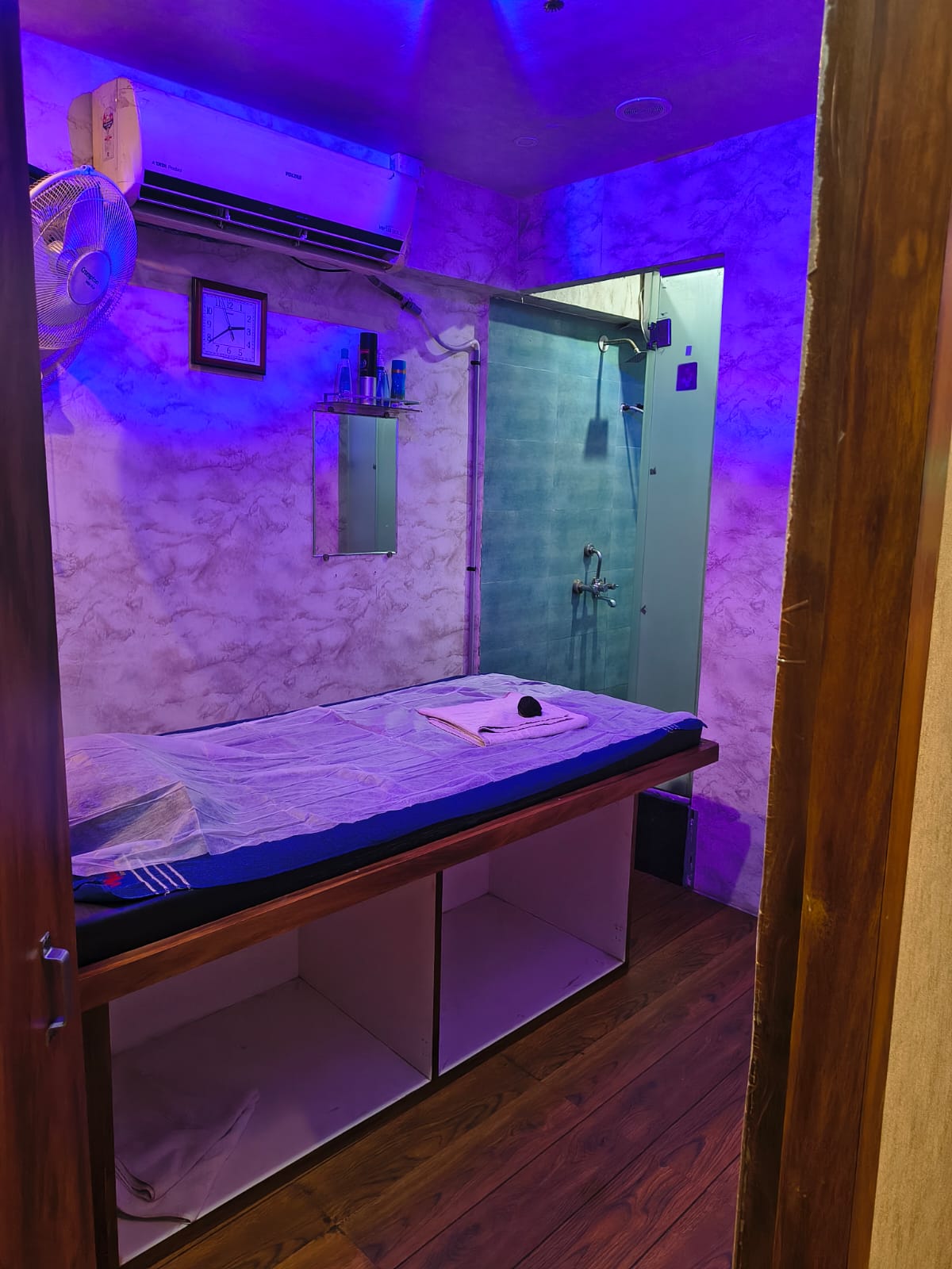 Private massage room with treatment bed and shower